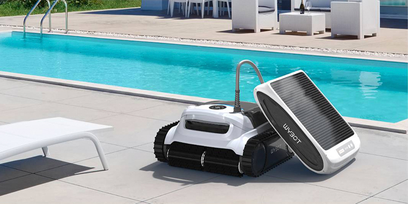 robot limpiafondos sin cable wybot m1 ultra, alimentado por un panel solar, situado en el exterior de la piscina